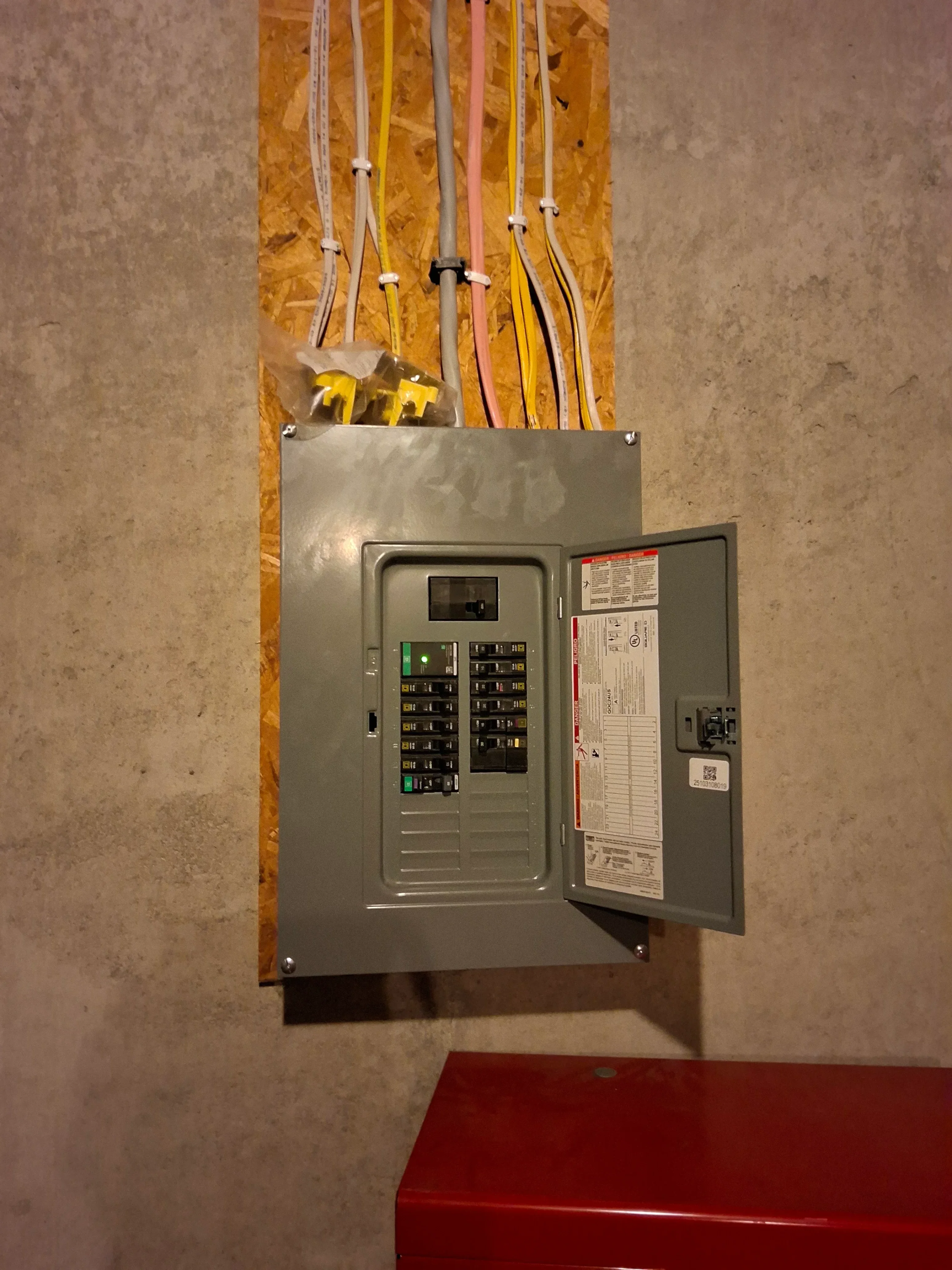Electrical panel with dual-row breakers and color-coded Romex cables secured with clamps