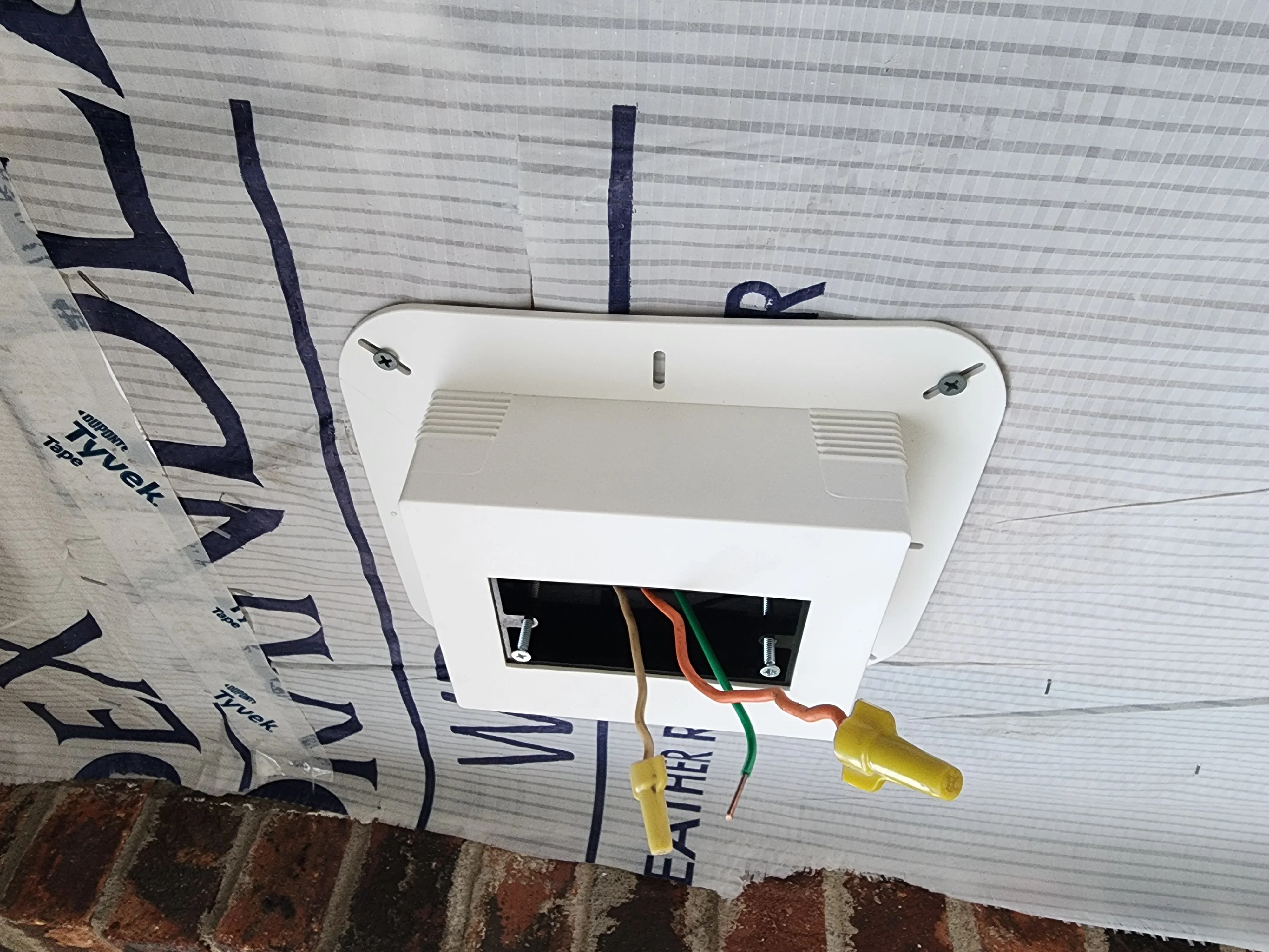 White outdoor electrical box with organized color-coded wiring and protective connectors installed on metal siding