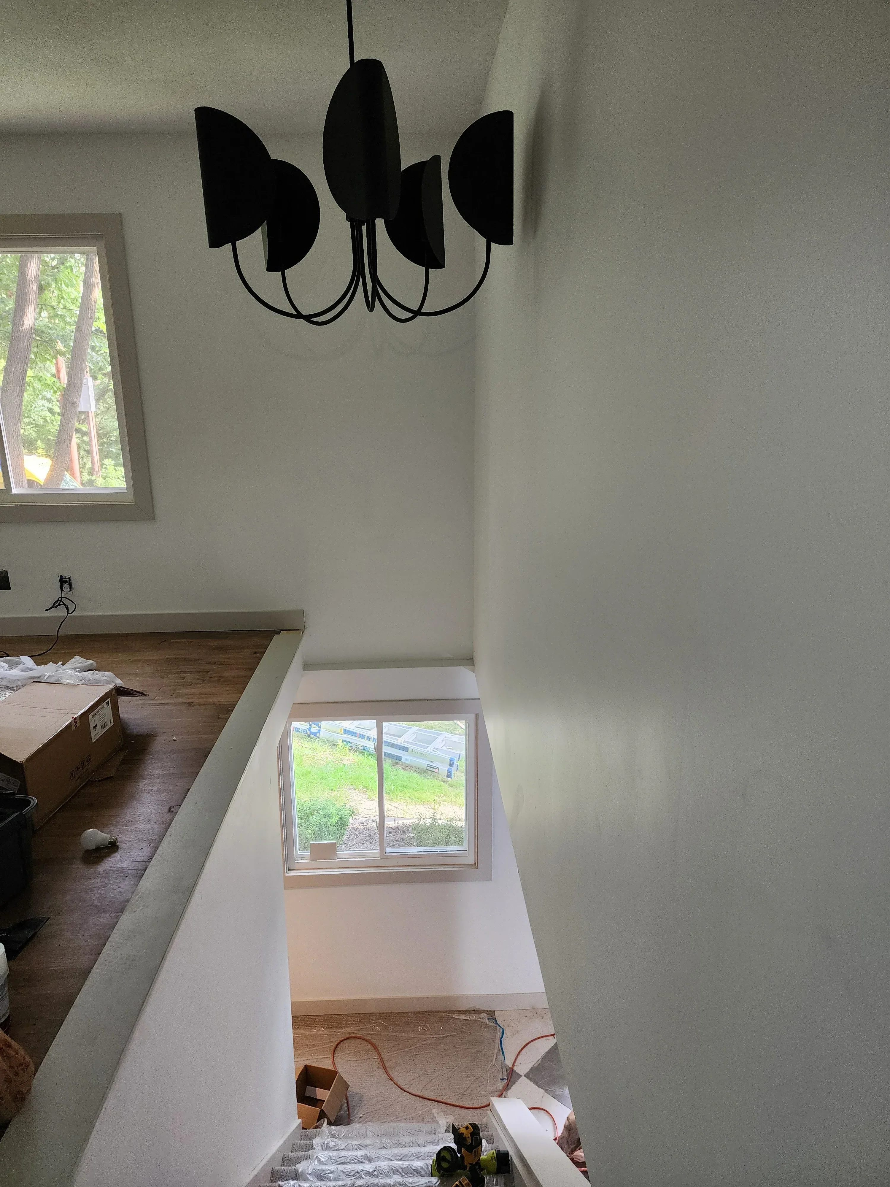 Black modern pendant lights with curved arms installed on white drywall ceiling