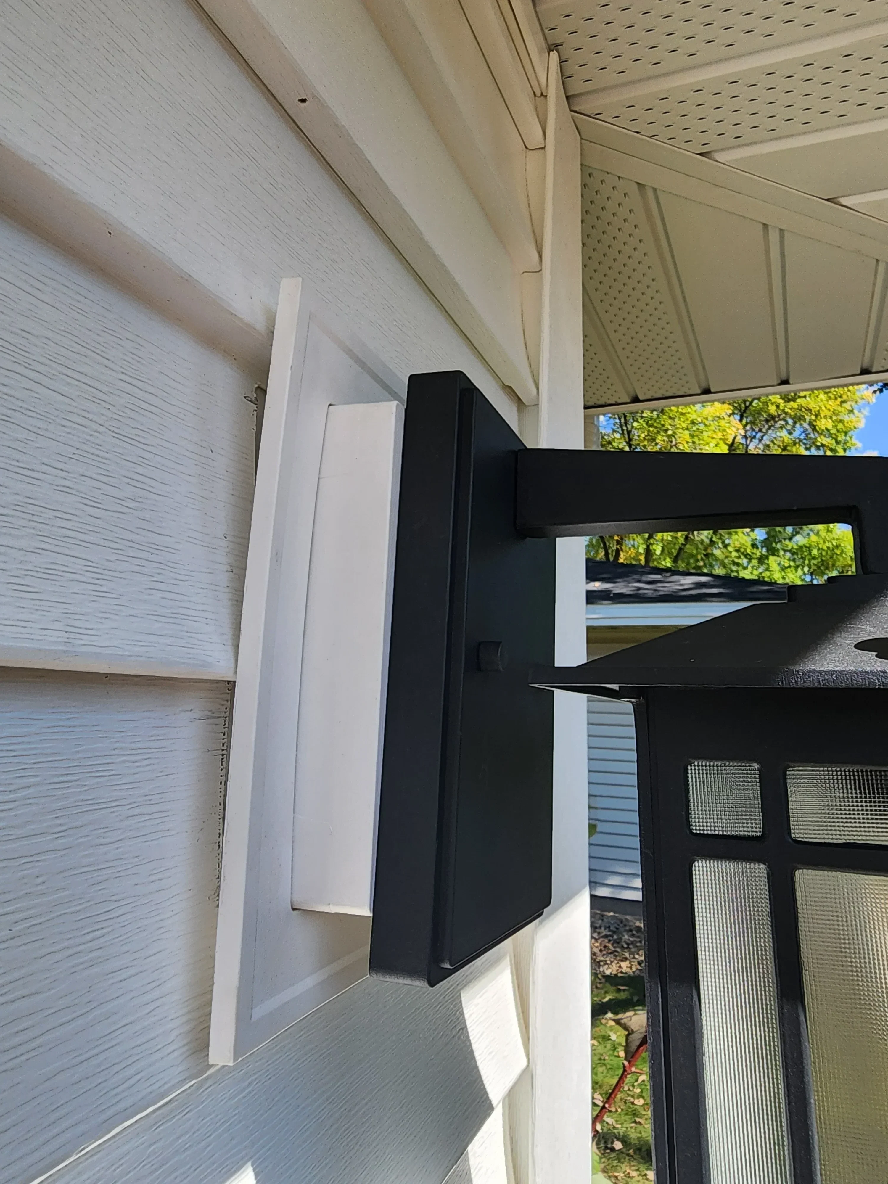 Black and white LED lighting fixture mounted on pergola with metal frame and composite decking