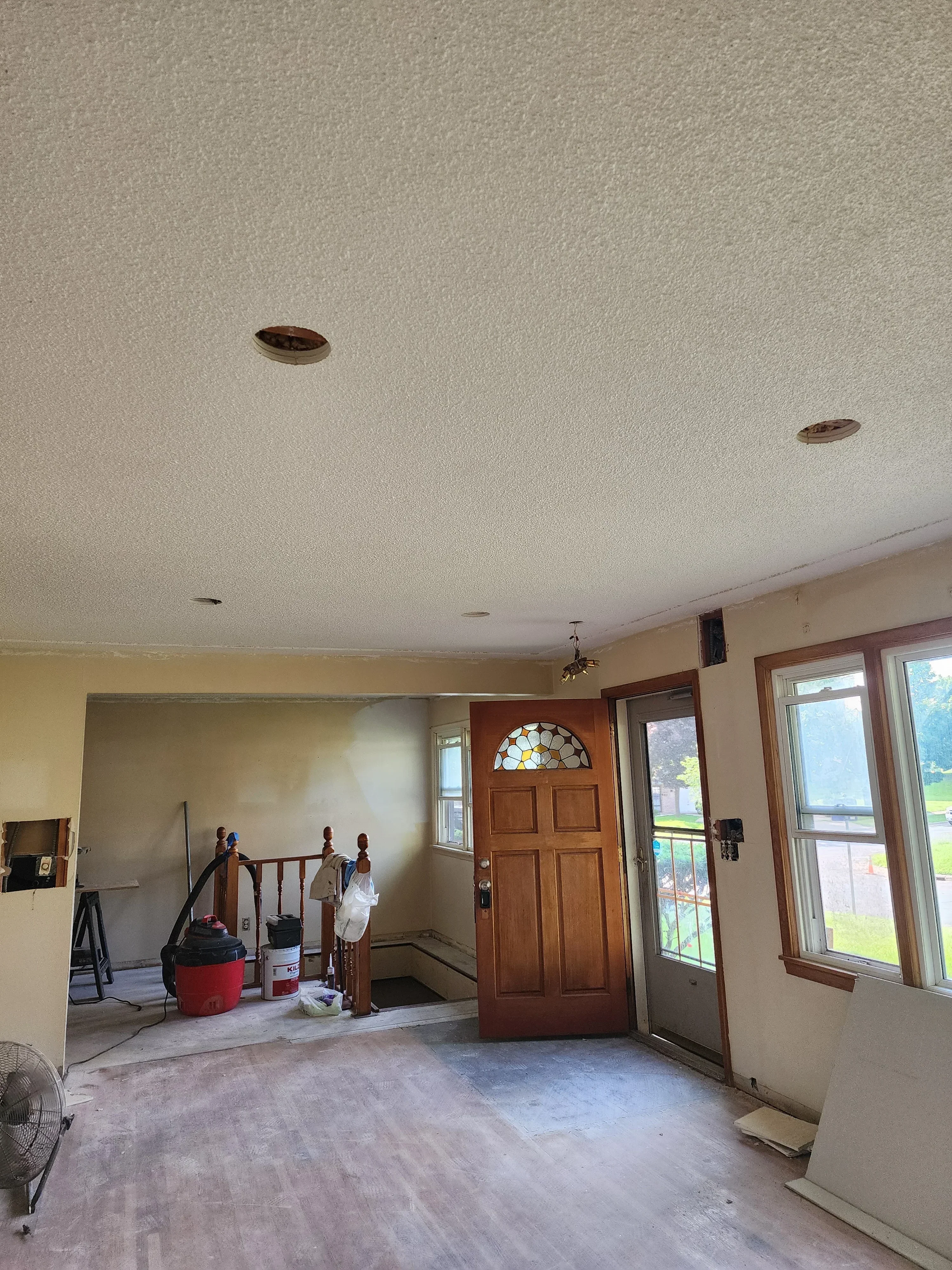 Newly installed electrical outlets on textured drywall in residential interior with wooden door and skylights