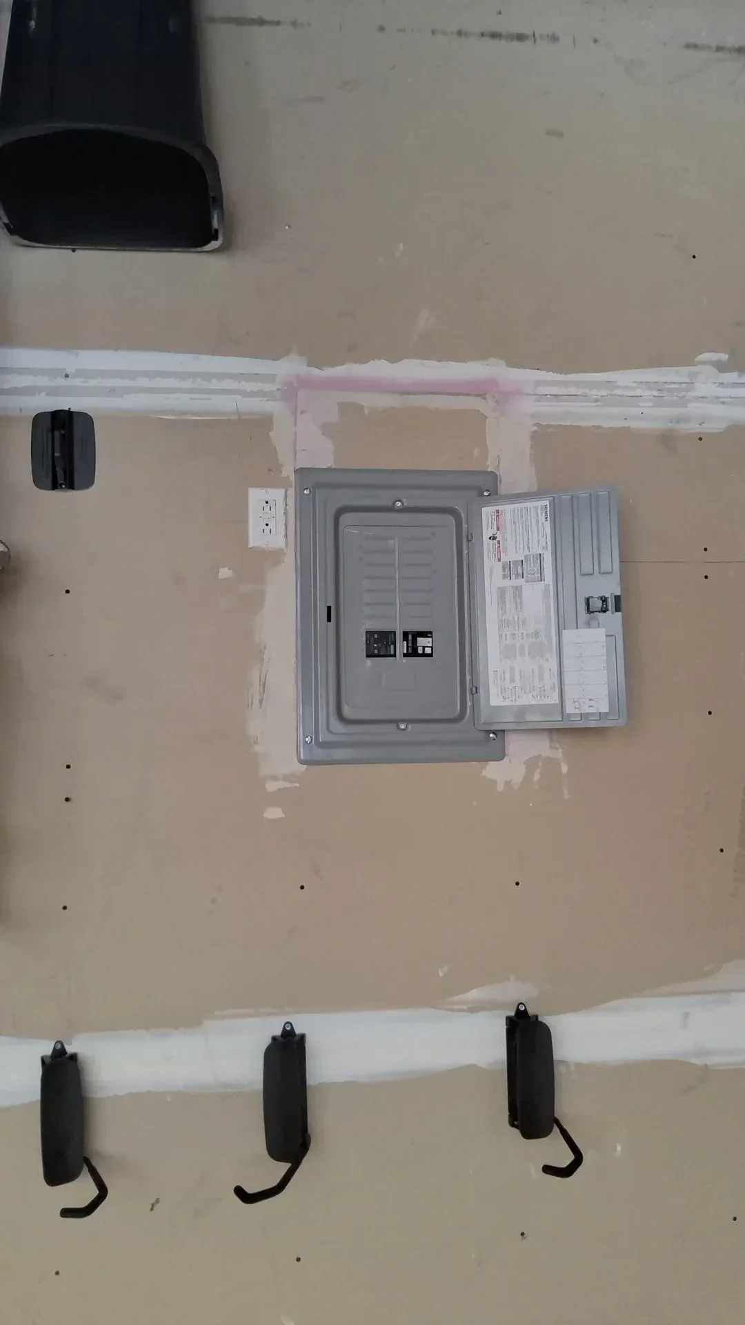 Electrical panel installation with PVC conduit, outlet boxes, and organized cable management on drywall