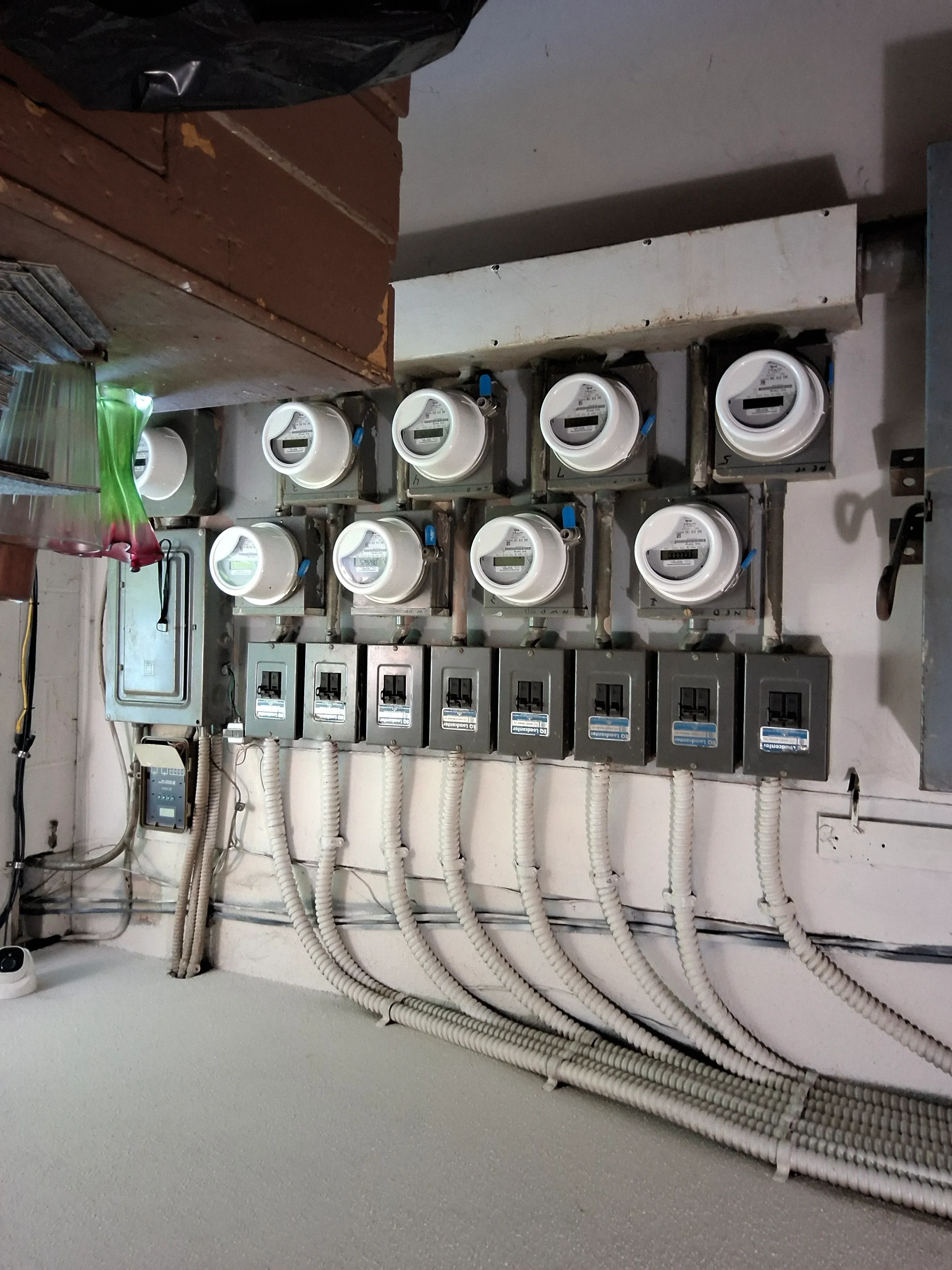 Multiple utility meters with breaker panels and white PVC conduit wiring installation