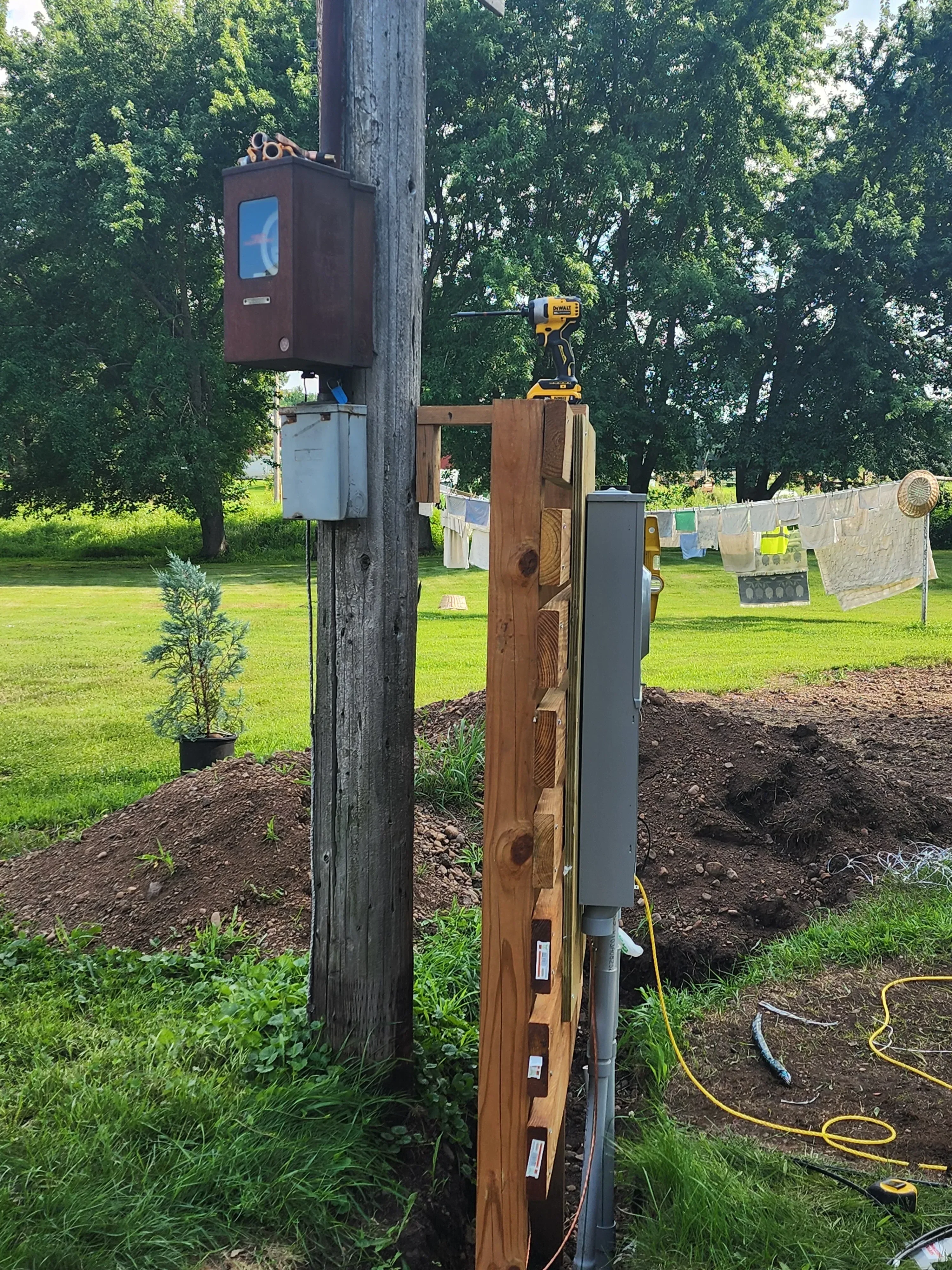 New electrical meter base and service disconnect installed on wooden mounting structure with conduit and grounding